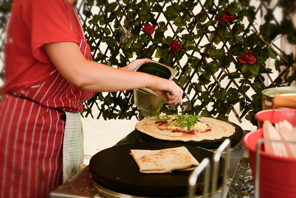 A person adding topping to a pizza base.