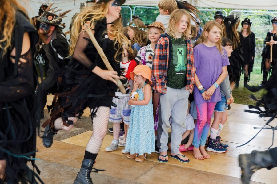 Morris dancers dancing around a group of children.