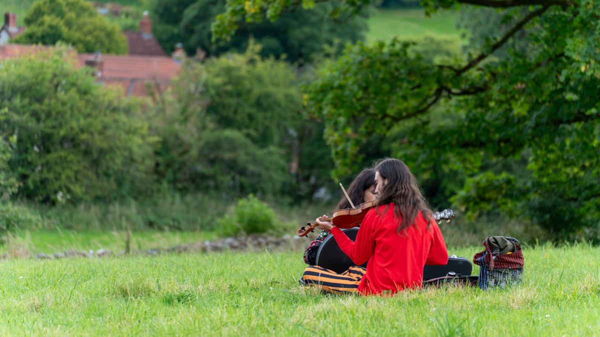 Two people in a field, one playing the violin.